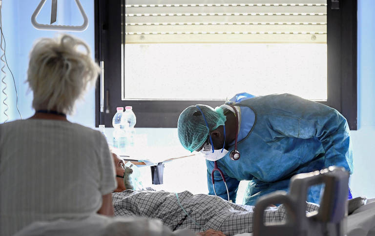 Profissional da área médica com equipamentos de proteção e paciente de Covid-19 em UTI no hospital Oglio Po, em Cremona, na Itália