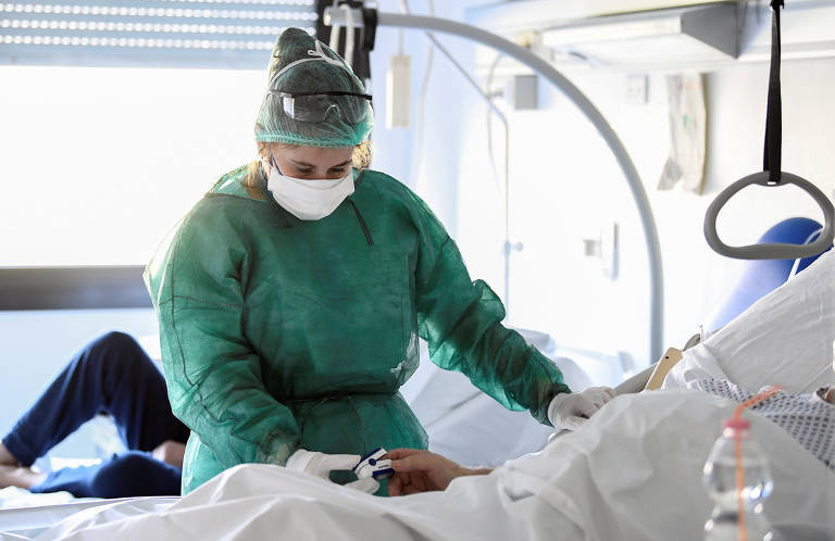 Profissional da área médica com equipamentos de proteção e paciente de Covid-19 em UTI no hospital Oglio Po, em Cremona, na Itália