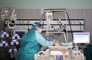Medical worker wearing a protective mask and suit treats a patient suffering from coronavirus disease (COVID-19) in an intensive care unit at the Oglio Po hospital in Cremona