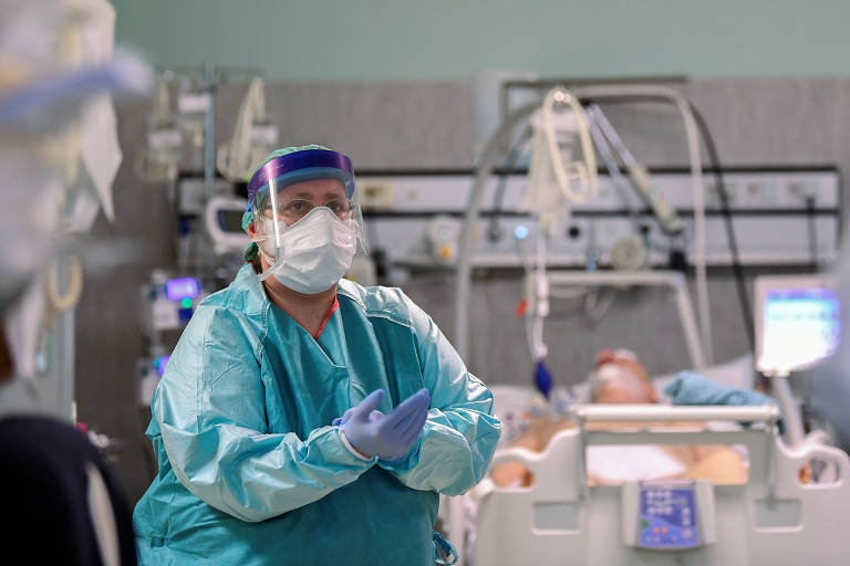 Profissionais da área médica com equipamentos de proteção e paciente de Covid-19 em UTI no hospital Oglio Po, em Cremona, na Itália