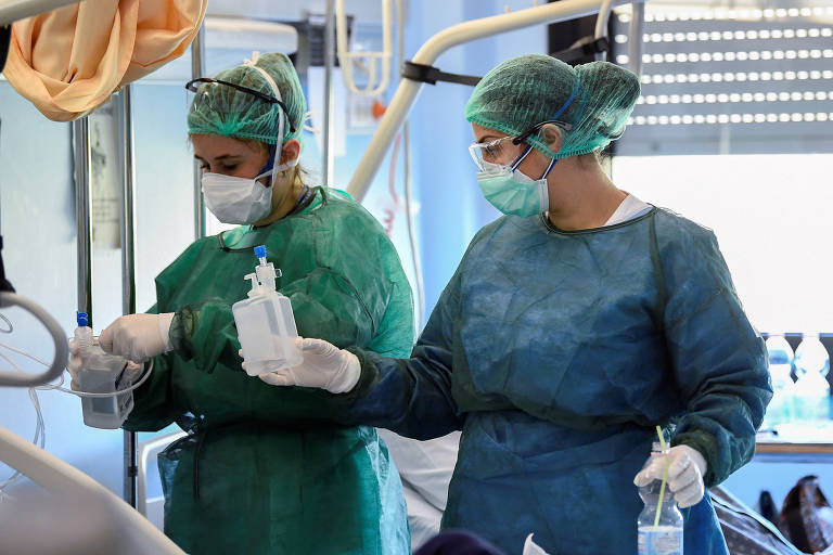 Profissionais da área médica com equipamentos de proteção e paciente de Covid-19 em UTI no hospital Oglio Po, em Cremona, na Itália