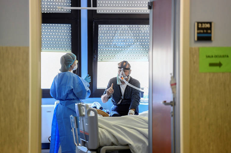 Profissionais da área médica com equipamentos de proteção e paciente de Covid-19 em UTI no hospital Oglio Po, em Cremona, na Itália