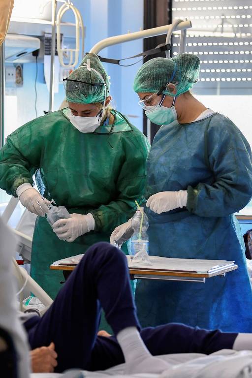 Profissional da área médica com equipamentos de proteção e paciente de Covid-19 em UTI no hospital Oglio Po, em Cremona, na Itália