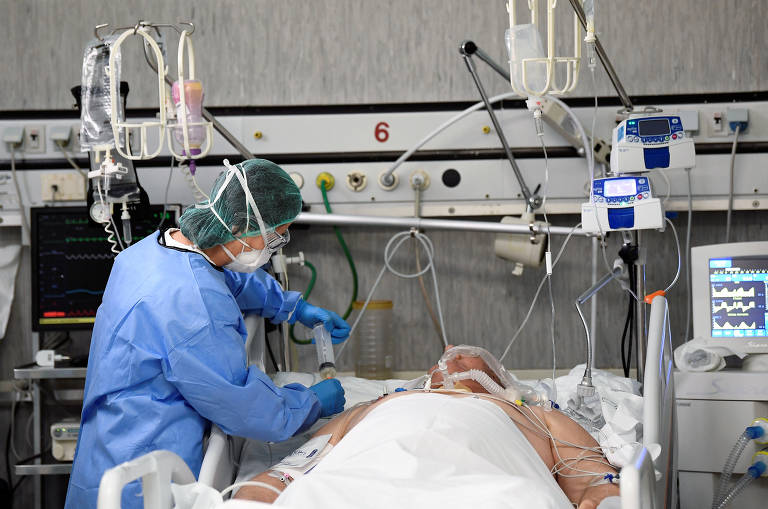 Profissional da área médica com equipamentos de proteção e paciente de Covid-19 em UTI no hospital Oglio Po, em Cremona, na Itália