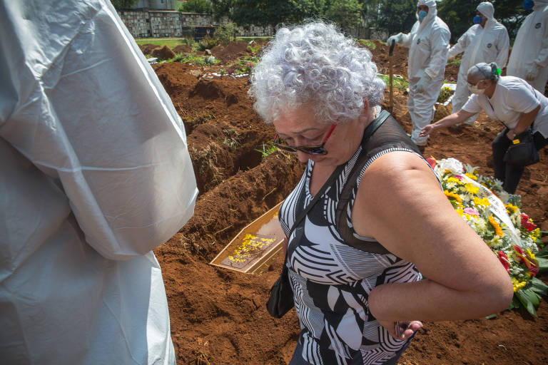 Antonia Fernandes de Souza, 62 anos, acompanha o sepultamento de seu irmão, Joao Geraldo Neto, 68, suspeito de ter morrido vítima da Covid-19