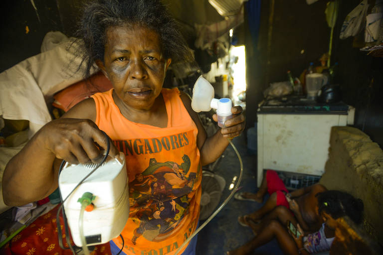 Eliane Maria da Silva, 58, asmática e hipertensa, tem dificuldade para ficar dentro da palafita minúscula em que mora, por causa do calor; ela enfrenta outras dificuldades, como a falta de luz que a impede de ligar o nebulizador