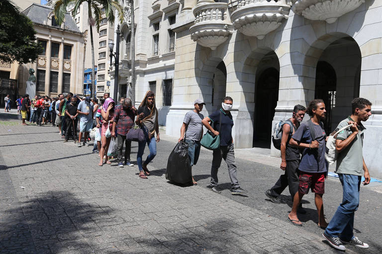 Moradores de rua fazem fila para receber comida distribuída por padres franciscanos, em frente ao largo de São Francisco, no centro de SP