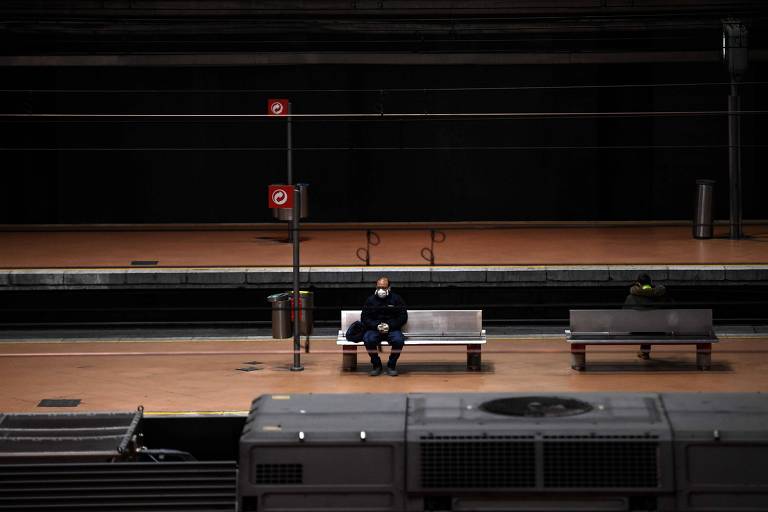 Um homem usando uma máscara facial senta-se em um banco em uma plataforma da estação ferroviária Atocha em Madri em 30 de março de 2020, durante um bloqueio nacional para impedir a propagação do novo coronavírus 