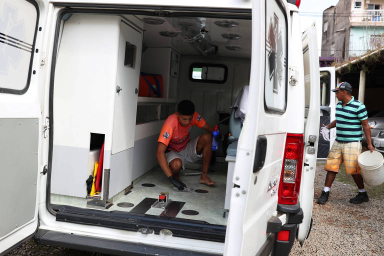 Pessoas limpam uma ambulância depois que os moradores da maior favela da cidade, Paraisópolis, contrataram um serviço médico privado 24 horas por dia para combater a doença por coronavírus  