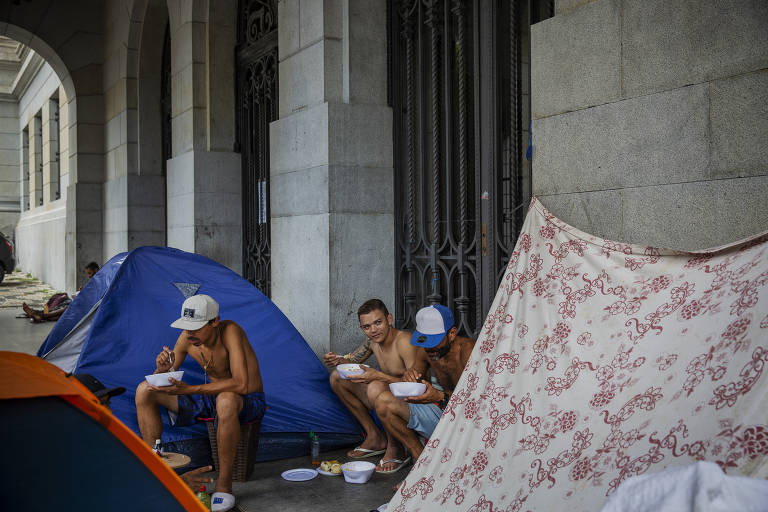 Moradores de rua comem a marmita em uma tenda montada no Largo São Francisco