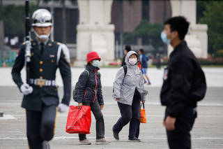 FILE PHOTO: Tourists wear protective face masks to protect themselves from coronavirus disease (COVID-19) while passing by a flag rising ceremony at Chiang Kai Shek Memorial Hall in Taipei