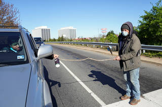 A man keeps his distance to prevent coronavirus spread as he panhandles in Falls Church, Virginia
