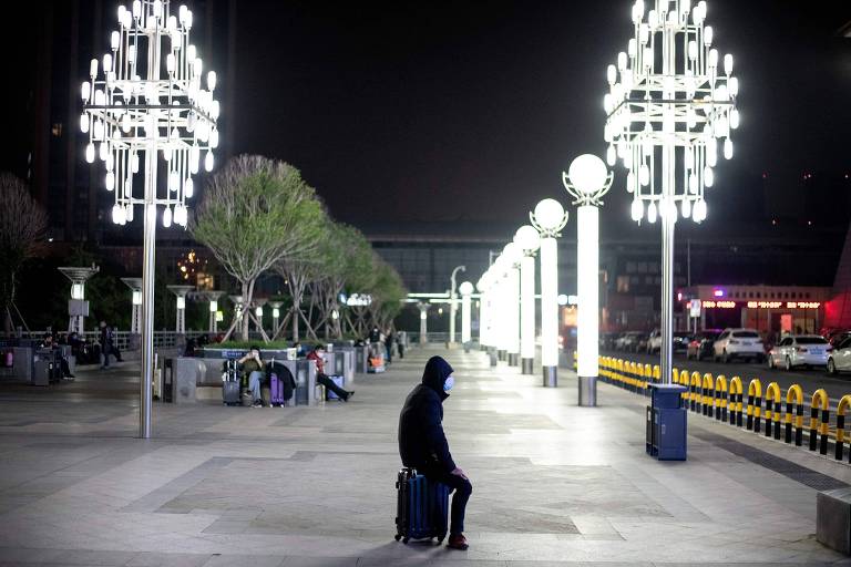 Passageiro de máscara aguarda na estação de trem de Wuhan na madrugada em que a quarentena foi suspena na cidade chinesa 