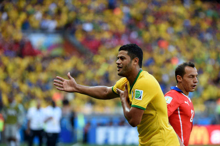 Hulk aponta o ombro, reclamando da marcação de toque de mão contra o Brasil em jogo com o Chie