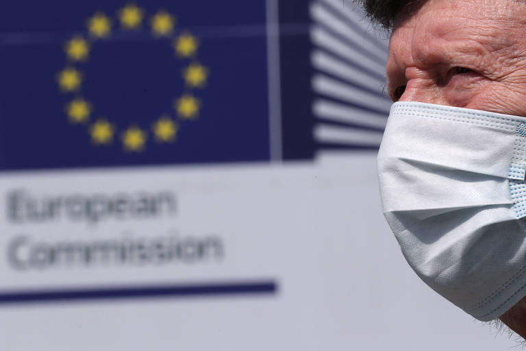 Homem vestindo máscara passa em frente à sede da Comissão Europeia em Bruxelas, na Bélgica 
