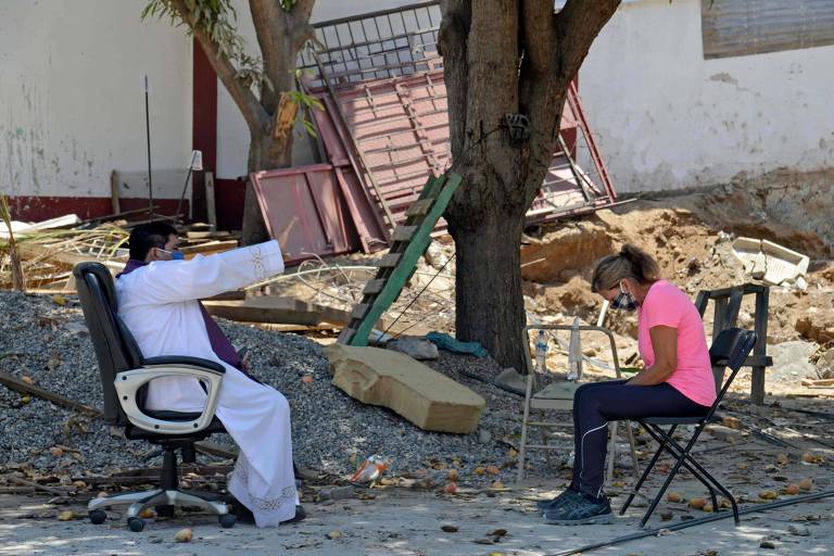 Com distanciamento, o padre Marco Antonio Galeana ouve a confissão de uma fiel na frente de uma igreja em Acapulco, no México