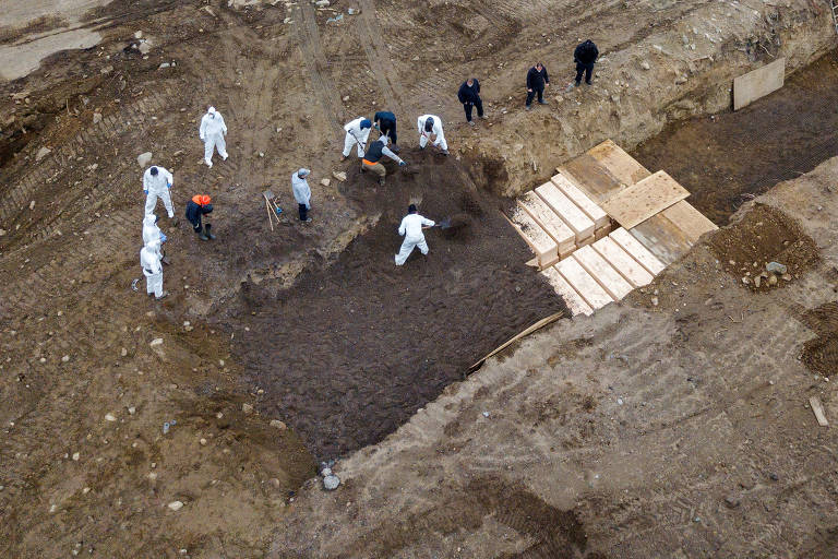 Coveiros enterram corpos em vala comum aberta em Hart Island, na cidade de Nova York