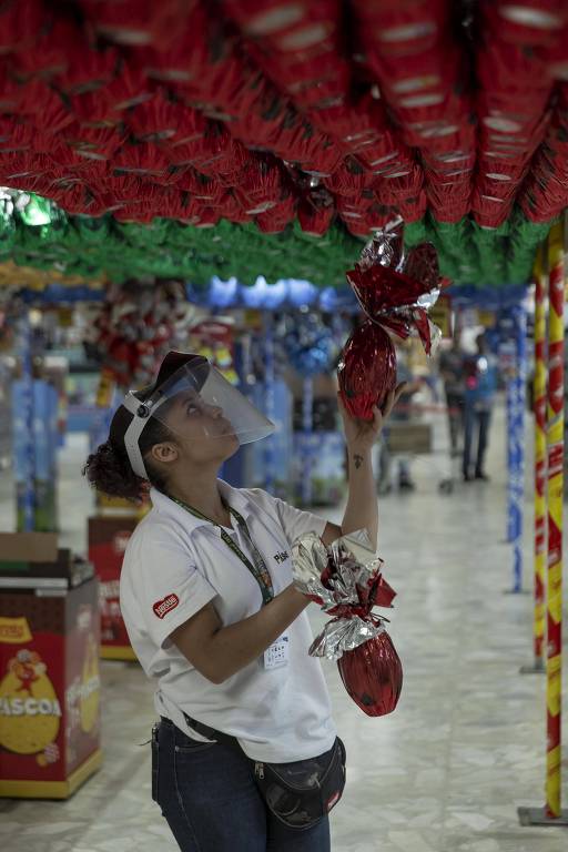 Funcionária da Nestlé repõe ovos de páscoa em supermercado em São Paulo; além do capacete, os repositores recebem uma pochete com itens como álcool em gel