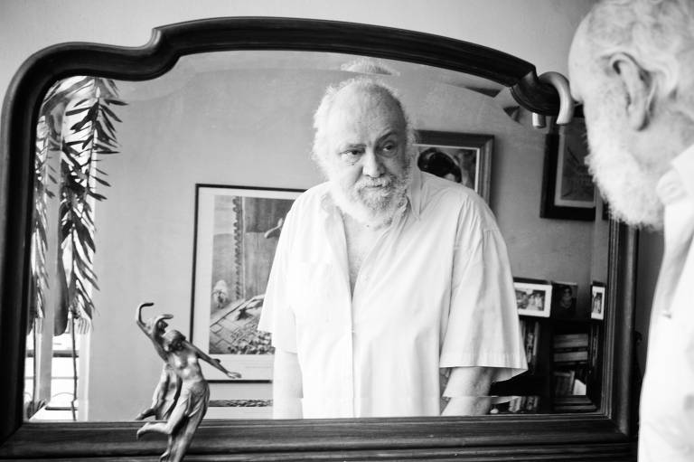 O compositor Aldir Blanc se olha no espelho, em sua casa, no Rio de Janeiro