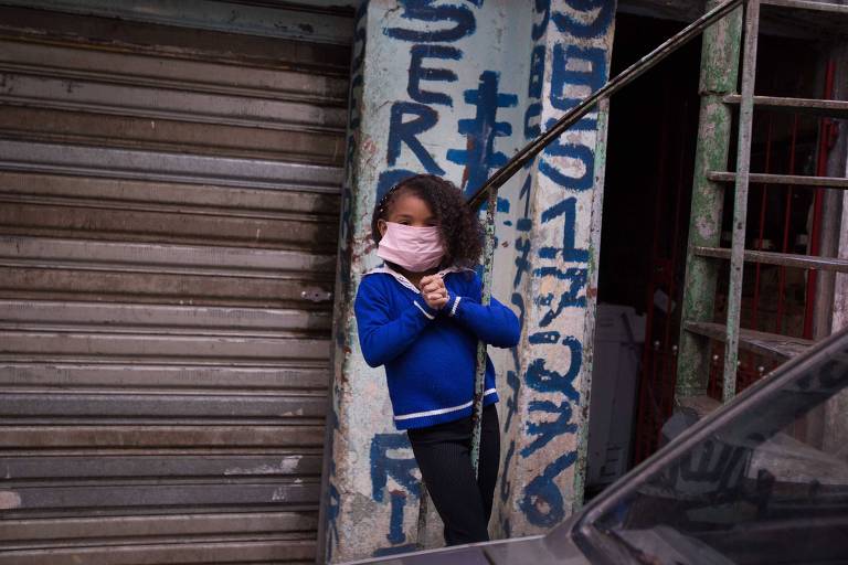 Menina usa máscara para evitar o Covid-19 na favela do Paraisópolis, zona sul de São Paulo