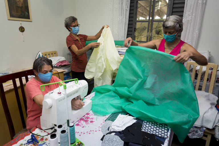 As irmãs Ana Lucia (camiseta listrada) e Alcir Bastos (vestido rosa) junto com uma vizinha costureira, Josefina Cattani, confeccionam aventais para os hospitais Santa Marcelina