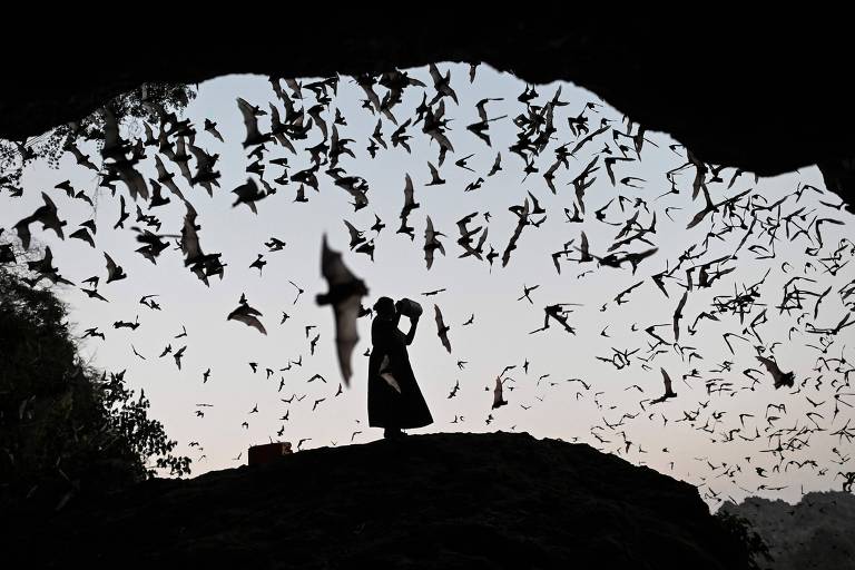 Vemos uma mulher pelo buraco de uma caverna; ela está cercada de morcegos que voam ao redor