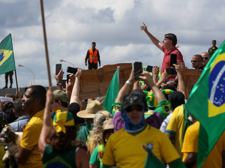 O presidente Jair Bolsonaro cumprimenta apoiadores que participavam de uma carreata em apoio ao presidente e contra as medidas de isolamento recomendadas por governos estaduais para tentar conter a pandemia do Coronavírus