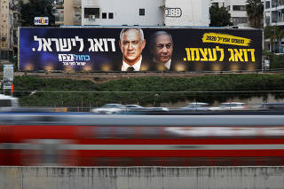 FILE PHOTO: Traffic moves past a Blue and White party election campaign poster, depicting party leader Benny Gantz, and Israeli Prime Minister Benjamin Netanyahu, in Tel Aviv