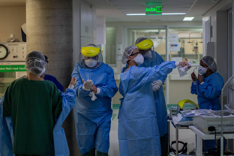 Médicos de aventais longos e azuis, máscaras, dentro do hospital