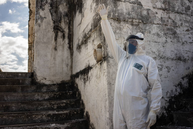Funcionário do cemitério do Caju, na zona norte do Rio de Janeiro, usa equipamentos de proteção