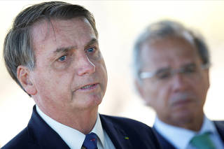 FILE PHOTO: Brazil's President Jair Bolsonaro speaks near Brazil's Economy Minister Paulo Guedes while leaving Alvorada Palace in Brasilia