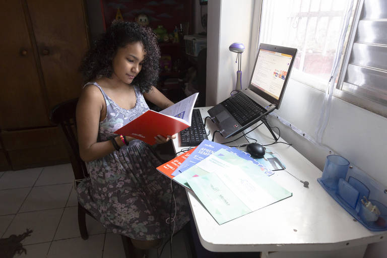 A aluna Gabriella Orion Felix Benz com apostilas e computador para o ensino à distância em São Paulo