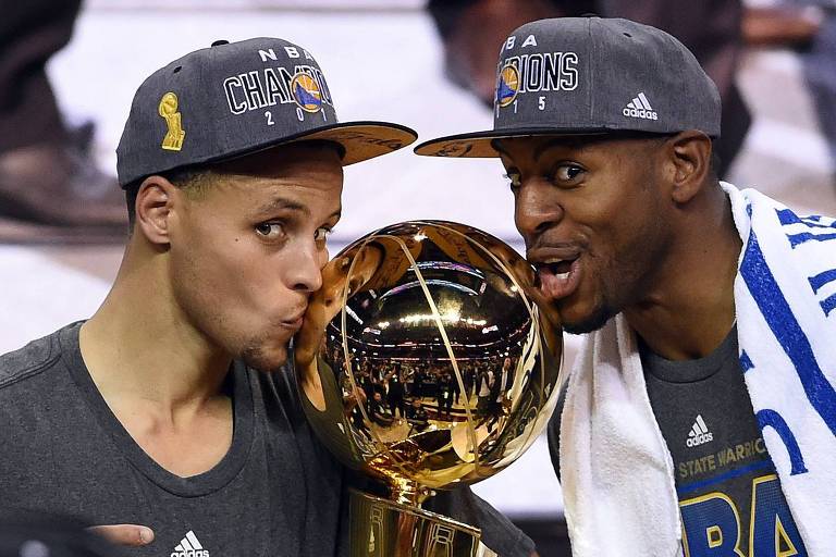 Stephen Curry (esq.) e Andre Iguodala beijam o troféu de campeões da NBA em 2015