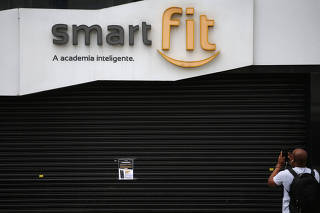 A man takes pictures of a notice inviting people to join Smart Fit gym's online workout classes at home, as the gym suspends training sessions as a protective measure to prevent the spread of the novel coronavirus disease (COVID-19) in Sao Paulo