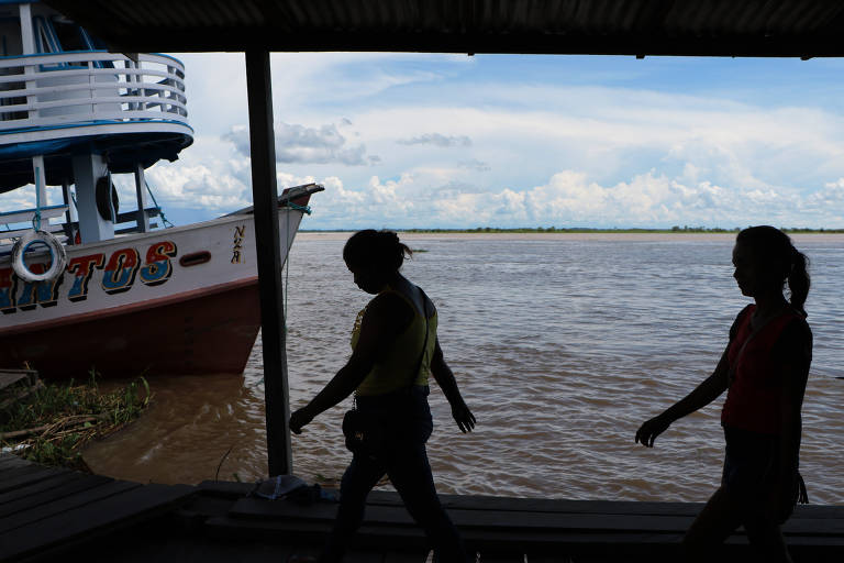 Vista do rio Solimões na orla de Manacapuru (AM) com pessoas caminhando sobre as casas flutuantes