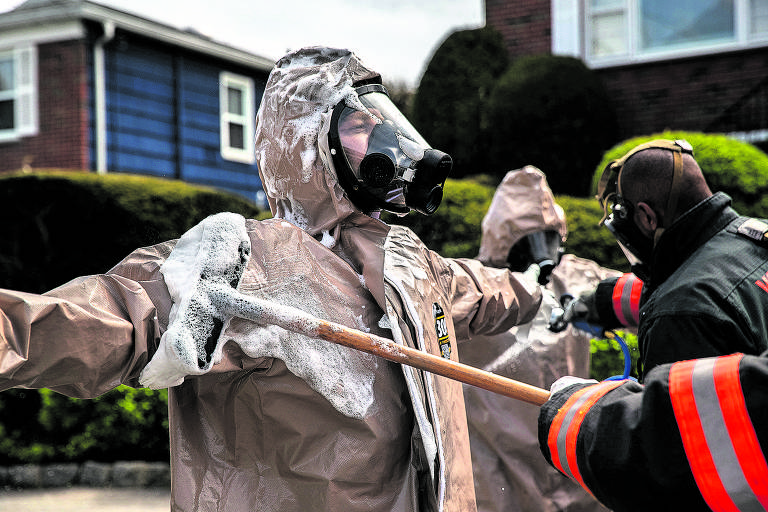 Socorristas de Yonkers descontaminam as suas roupas após transportarem para o hospital um paciente com suspeita de Covid-19
