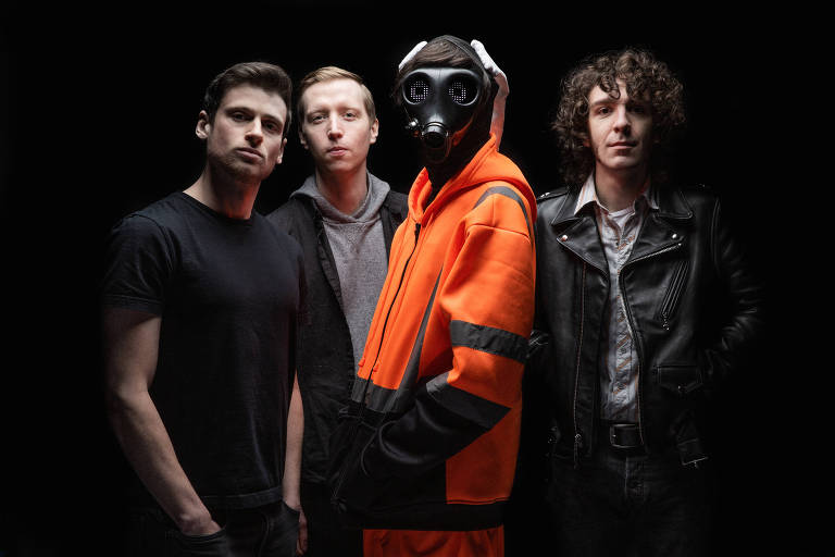 quatro pessoas e uma delas de laranja com uma máscara preta