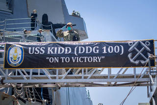 U.S. Navy sailor salutes the national ensign as he disembarks the guided-missile destroyer USS Kidd in San Diego
