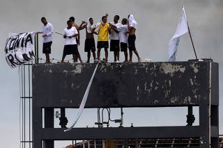 Inmates at Puraquequara's prison are seen on the roof with a prison worker as a hostage during a riot following an outbreak of the coronavirus disease (COVID-19), in Manuas