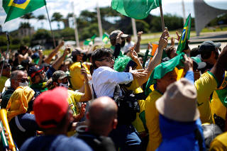 Brazilian photographer Dida Sampaio is pushed off of the top of a ladder by supporters of far-right Brazilian President Jair Bolsonaro during a protest, in Brasilia