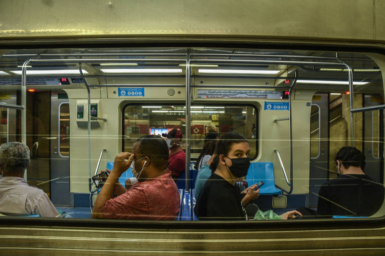 Várias pessoas dentro do metrô com máscaras de proteção facial
