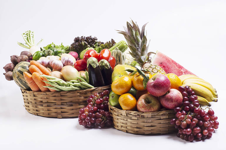 Duas cestas de palha redondas cheias de frutas e legumes