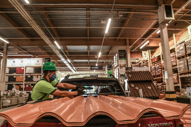 Lojas e shoppings fazendo drive-thru; Funcionário coloca produtos adquiridos no porta-malas de um cliente