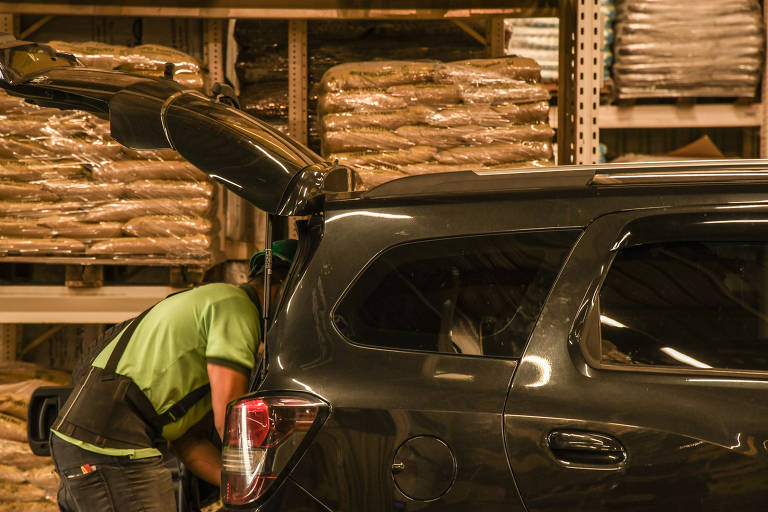 Lojas e shoppings fazendo drive-thru; Funcionário coloca produtos adquiridos no porta-malas de um cliente