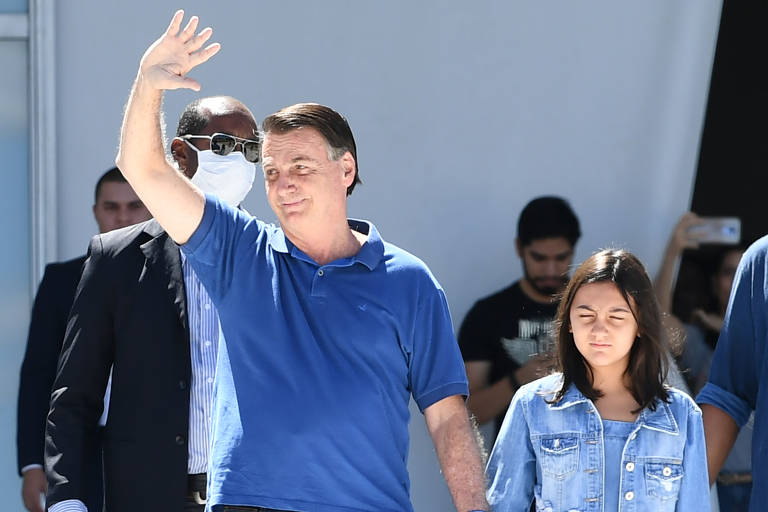 Bolsonaro acena enquanto caminha ao lado da garota