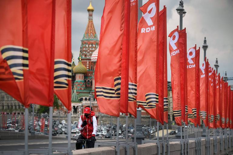 Ciclista em ponte com bandeiras vermelhas devido à comemoração do Dia da Vitória, em Moscou
