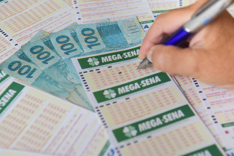 Bilhete de aposta na Mega Sena sobre notas de R$ 100 