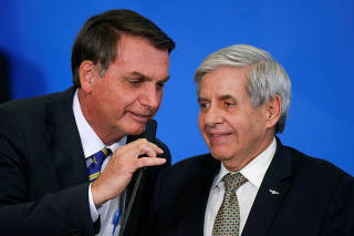 Brazil's President Jair Bolsonaro speaks with Brazil's Minister of Institutional Security Augusto Heleno during a ceremony at the Planalto Palace in Brasilia