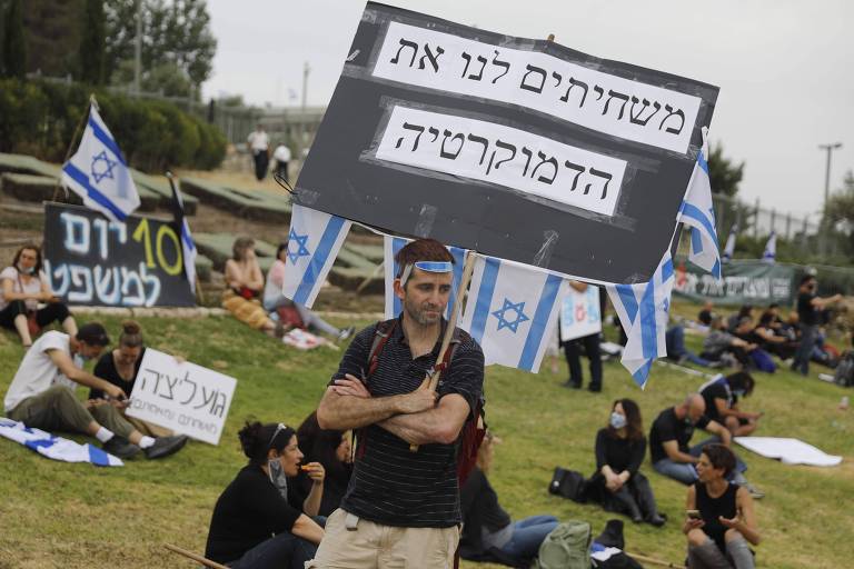 Manifestante com proteção facial protesta contra o novo governo de Israel em frente ao Parlamento do país