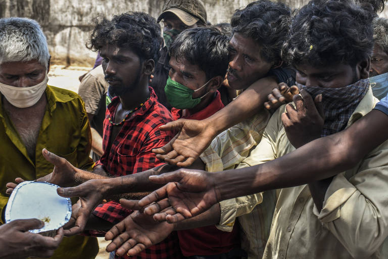 Trabalhadores migrantes, retidos em Mumbai devido ao 'lockdown' na Índia, aglomeram-se para receber comida em Dharavi